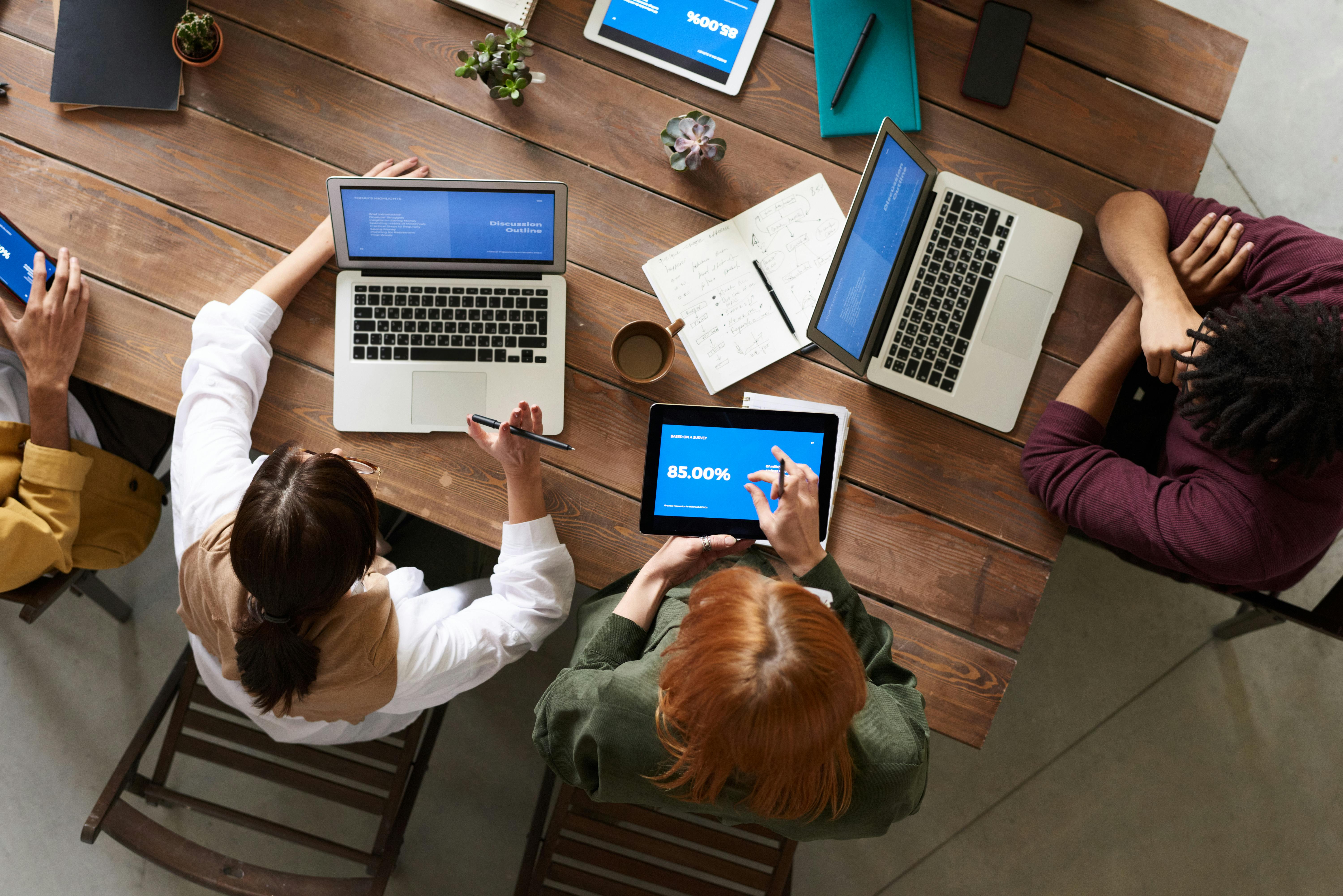Image of people working together on their laptops at a desk.